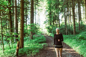 Woman running through forest in black clothes