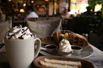 A plate of waffle with banana, whipping cream, blueberry and syrup, delicious, yummy