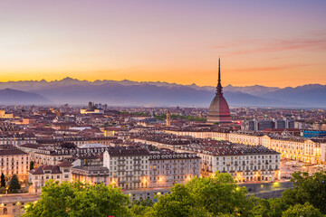 Cityscape of Torino (Turin, Italy) at dusk with colorful moody sky. The Mole Antonelliana towering on the illuminated city below. - obrazy, fototapety, plakaty
