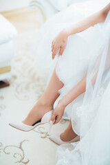 Fototapeta na wymiar The charming bride wears a wedding shoes