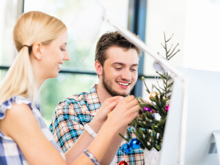 Young man decorating christmas tree in office