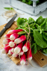 Bunch of fresh raw ripe young radishes with leaves on a light background. Selective focus.