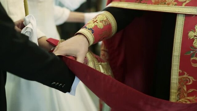 The priest lays his hands on the newlyweds