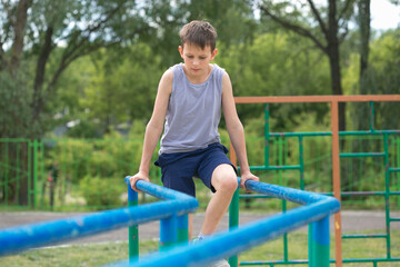 The teenager in a vest is engaged on uneven bars