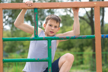 Obraz premium A teenager in a T-shirt is engaged in gymnastics on a horizontal bar