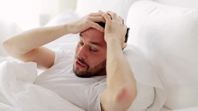 man waking up in bed at home