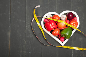 Vegetables in the heart. Peppers, tomatoes, garlic, eggplant, onions and radishes on a black background