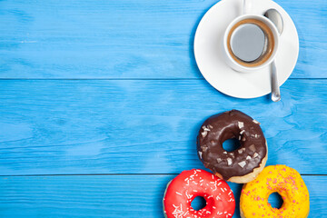 Fototapeta na wymiar Cup with coffee and donuts on a blue wooden table