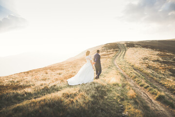 Obraz premium Beautiful gorgeous bride posing to groom and having fun, luxury ceremony at mountains with amazing view, space for text, wedding couple