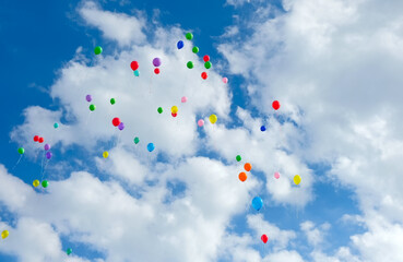 Lots of colorful balloons flying on cloudy blue sky