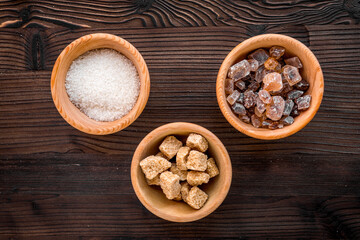 lumps of sugar in bowls on wooden table background top view