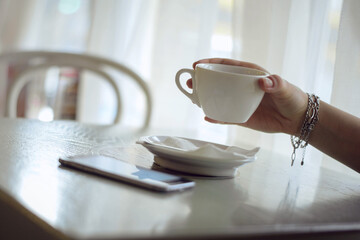 A hand holds a cup of coffee in a coffee house