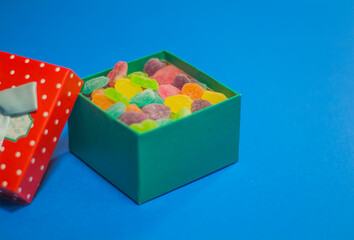Mixed colorful candies, gift and jelly on copy space background.