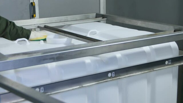 Worker in Uniform Puts Plastic Container into Metal Carcass