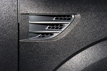 Surface of powerful black sub textured car bodywork, detail of vehicle side and fender with air...