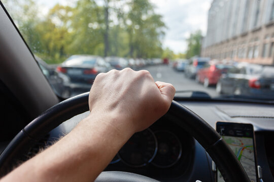 Male hand on the steering wheel while the car is in motion.