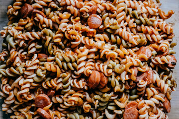 .Macaroni and tomato sauce garnished with sausage pieces and gratin with mozzarella cheese. Lifestyle portrait.