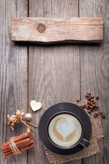 cup of cappuccino coffee on old vintage wooden table, dry flower , cinnamon, top view