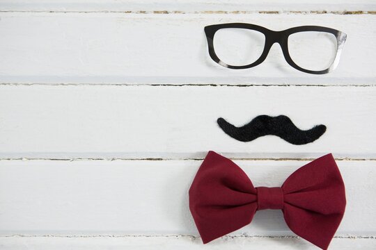Close up of eyeglasses and bow tie with mustache on table