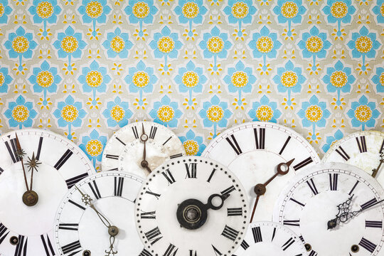 Collection of ancient clock faces in front of retro wallpaper
