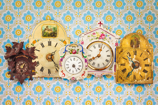 Collection of colorful hanging clocks in front of retro wallpaper