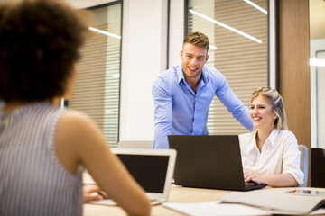 Young business people using laptop and smiling while working in office