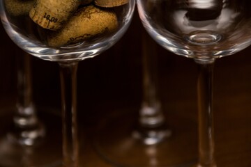 Empty wine glasses and a glass filled with wine corks on a dark woody background