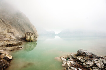 Kawah Ijen Volcano, East Java, Indonesia. Sulfur lake with poisonous fumes and fog in a crater of volcano. Dangerous place on the Earth.