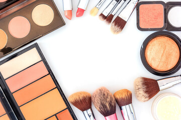 A collection of brush, make up and cosmetic beauty products arranged on a white background, with empty space at side