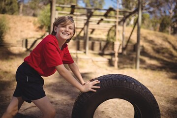 Portrait of smiling girl exercising with huge tyre
