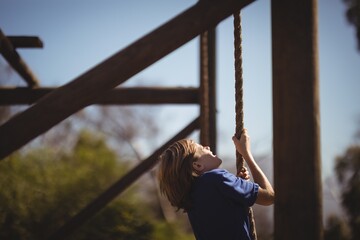 Determined girl climbing rope during obstacle course