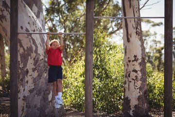 Boy performing pull-ups on bar during obstacle course