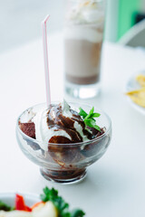 Nice banana and chocolate dessert in a glass bowl on white table.