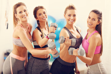 Group of smiling people lifting barbells