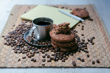 coffee cup and coffee beans on wooden table with cookies and notepad