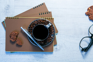 Blank spiral notepads, Cup of Coffee and Pen on Wood Background
