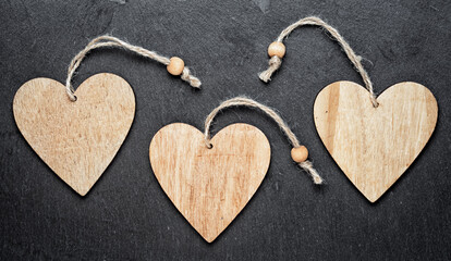 Obraz premium three wooden hearts on a black background. copy space for your text inside the hearts.