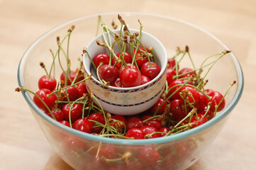 Many cherries lie and dry in a glass bowl and ceramic cup
