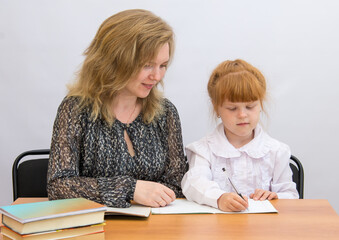 Fototapeta premium Little girl with mum sitting at a desk