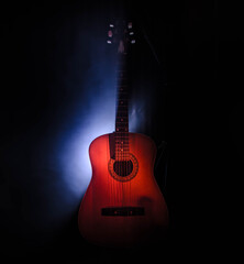 Naklejka premium Music concept. Acoustic guitar isolated on a dark background under beam of light with smoke with copy space. Guitar Strings, close up. Selective focus. Fire effects