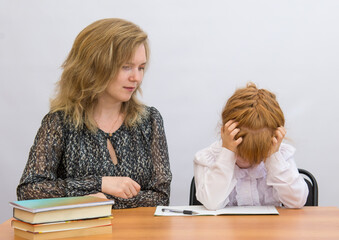 Little girl with mum sitting at a desk with his head in his hands