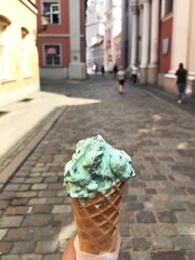 Holding mint chocolate chip ice-cream cone, Polish ice cream lody, walking in old town of Poland - obrazy, fototapety, plakaty