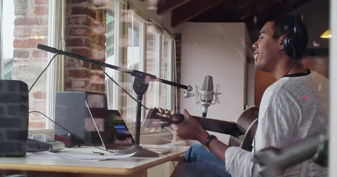 black man creative musician at home studio works by playing,singing and recording guitar with notebook tablet and microphone indoor in modern industrial house. 4k handheld back video shot