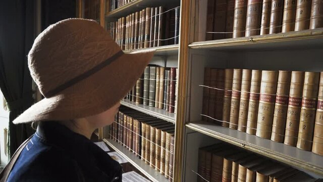 Woman checking ancient books in old library