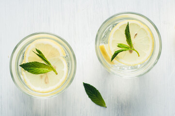 Water with lemon and peppermint in the glass on a bright background. Diet or weight loss concept