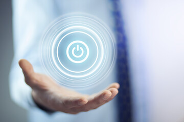 Businessman on blurred background holding render power button with his hand