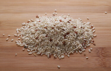 Integral, brown rice pile isolated on wooden table