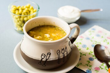 Vegetable soup with sour cream, pea pearl on blue background.