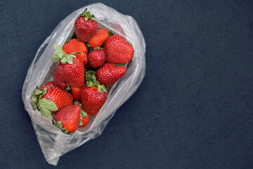 fresh ripe useful fruit strawberry in tray closeup on a dark blue background