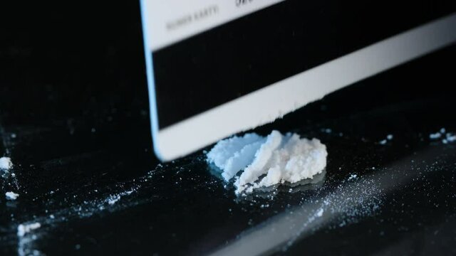 Drug Abuse. Forming two lines of drug powder with a plastic card. Problems with drugs concept. Black background. Close-up macro shot.